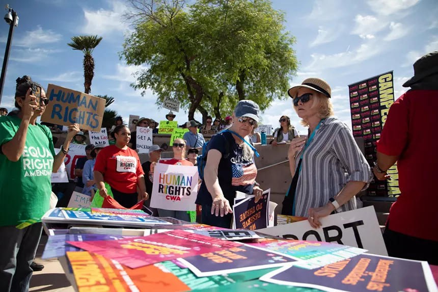 people at a protest around a table with protest signs laid flat on it