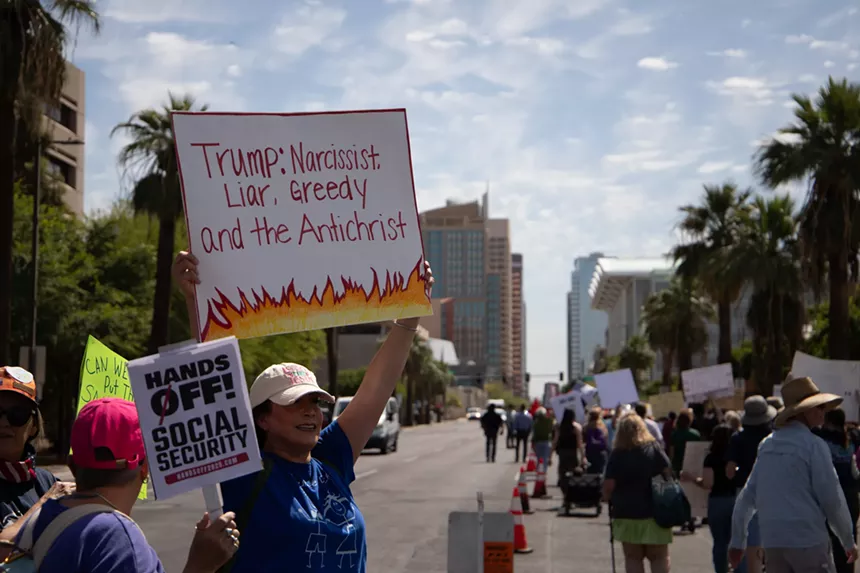 A protester holds a sign that says "Trump: Narcissist, liar, greedy and the antichrist"