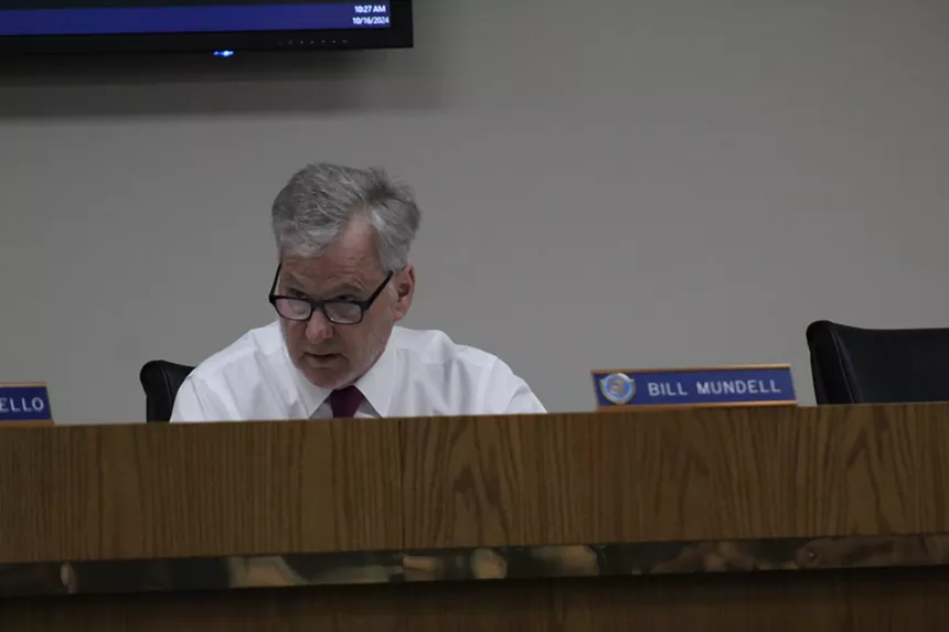 a man on a dais with a nameplate reading bill mundell