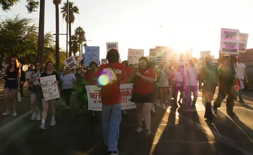 protesters walk down a street holding signs