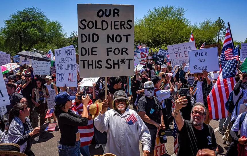 a protester holds a sign that says "our soldiers did not die for this shit"