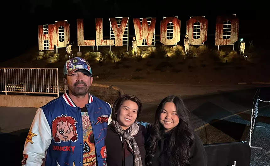 a man and two women stand in front of a haunted hollywood sign