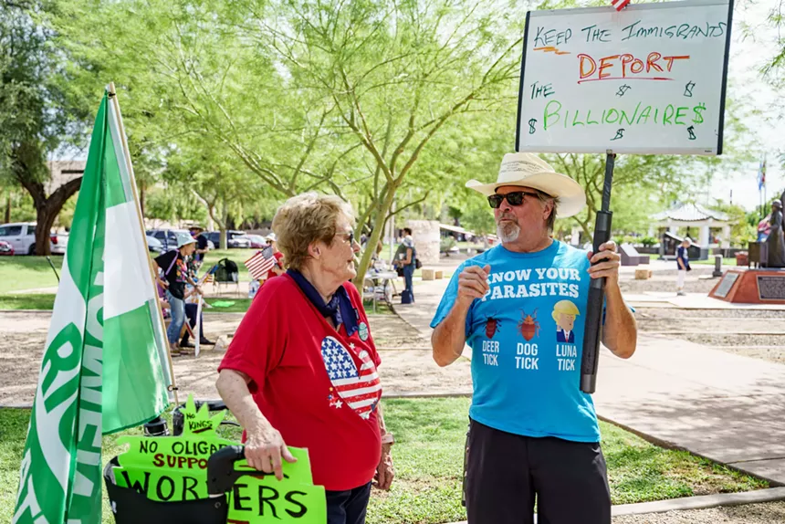a man holds a sign that says "keep the immigrants, deport the billionaires"