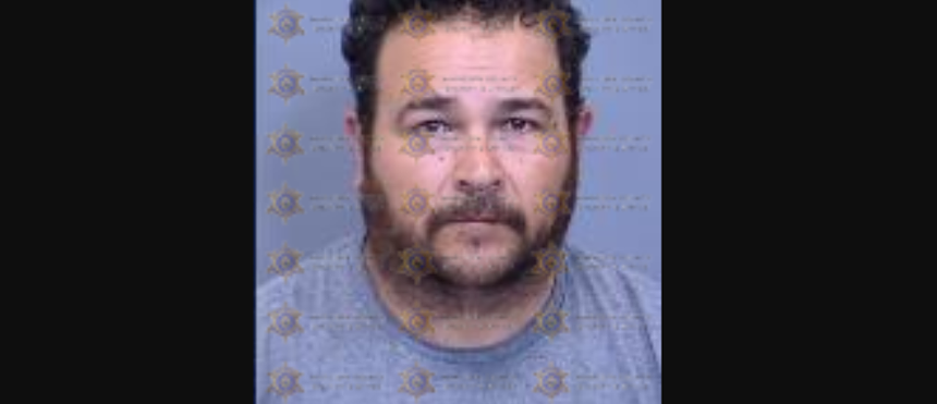 a mugshot of a bearded man in his 40s