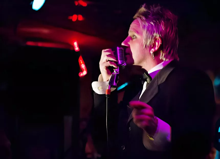 A man sings into a vintage microphone.