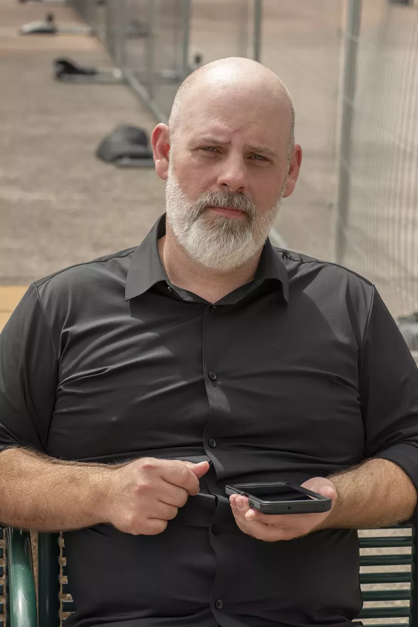 A man in a black shirt sits on a park bench