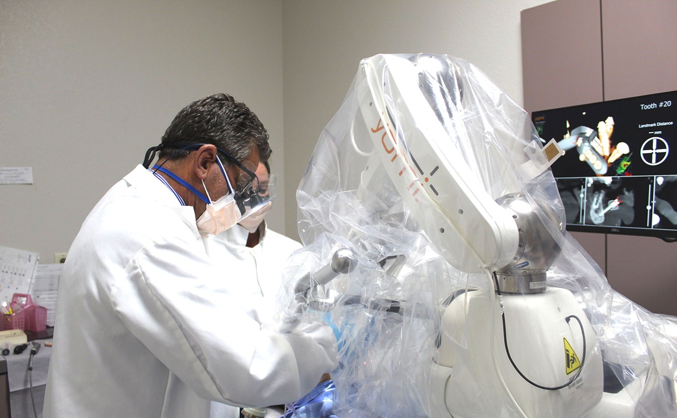 Dr. Leslie Fish and his robot assistant, Yomi, perform a dental implant surgery at Fish's Chander practice on Thursday morning.