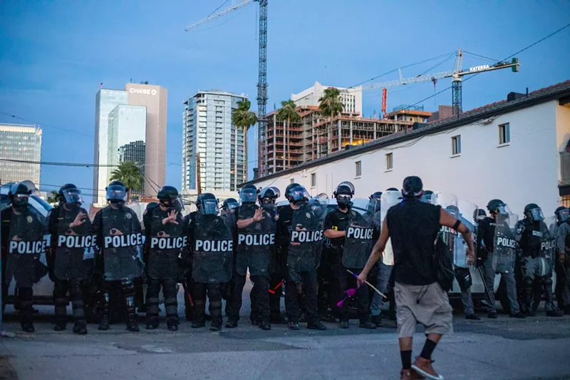 Image: A protester confronts Phoenix police in riot gear just before an 8 p.m. curfew during Black Lives Matter protests in May 2020.