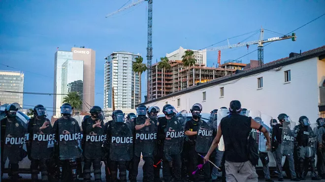 A protester confronts Phoenix police in riot gear just before an 8 p.m. curfew during Black Lives Matter protests in May 2020.