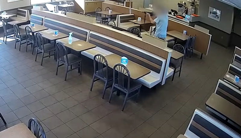 Image: a man in a fast food restaurant fires an assault rifle