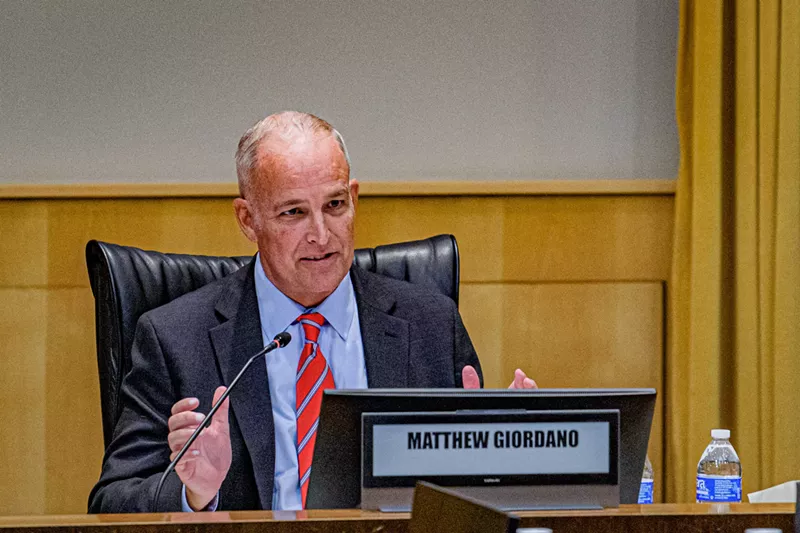 Image: a man in a suit at a meeting