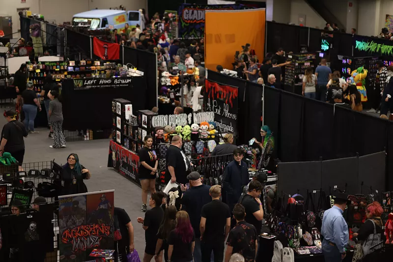 Image: A crowd of people inside the vendor hall of a convention center.