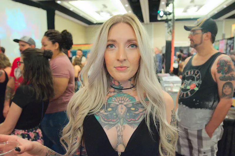 Image: A blonde woman with a chest-piece tattoo.